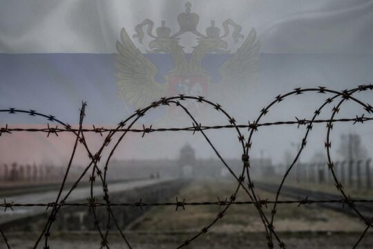 Rostiger Stacheldraht und neblige Landschaft, überlagert von einem undeutlichen Symbol: der Lafontaine Holocaust Vergleich, der Empörung auslöst.