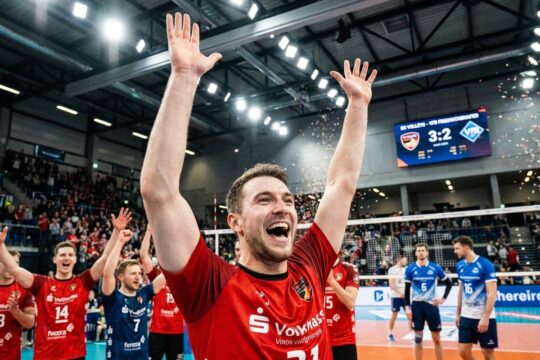 BR Volleys Spieler in Rot jubelt. BR Volleys Sieg gegen Friedrichshafen: hart erkämpft. Teamkollegen feiern, Gegner sind enttäuscht.