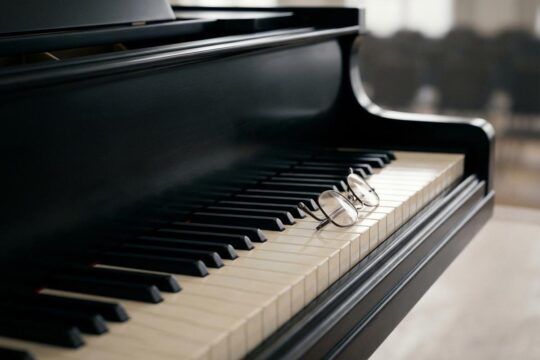 Die unberührte Tastatur eines schwarzen Flügels mit Lesebrille liegt still im melancholischen Licht. Ein Symbol des Abschieds, da Richie Beirach gestorben ist.