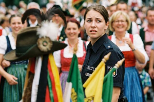 Eine Polizistin blickt auf dem Schützenfest Hannover sichtlich unbehaglich und überrascht in die Menge. Ihr Gesichtsausdruck deutet auf sexuelle Belästigung hin.