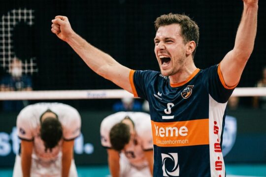 Ein BR Volleys Spieler in ekstatischer Feierpose jubelt über den hart erkämpften BR Volleys Sieg Friedrichshafen, während die Gegner enttäuscht sind.
