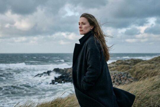 Marleen Lohse steht nachdenklich an der rauen Nordseeküste, blickt in die Ferne und sinniert über einen Marleen Lohse Nord bei Nordwest Ausstieg.