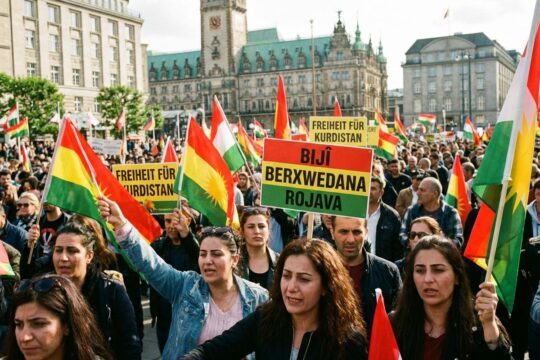 Entschlossene Gesichter bei der pro-kurdischen Demonstration Hamburg: Viele schwenken Fahnen und Plakate vor ikonischer Architektur.