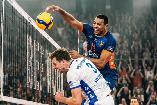 Ein BR Volleys Spieler dominiert am Netz und blockt einen Ball gegen den VfB Friedrichshafen. Das packende Volleyball-Duell der Rivalen im entscheidenden Moment.