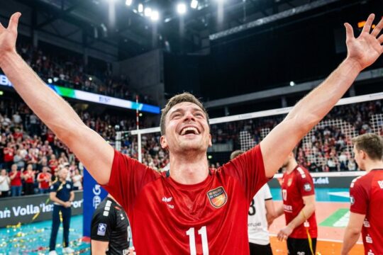 Ekstatischer BR Volleys Spieler im roten Trikot jubelt mit erhobenen Armen über den BR Volleys Sieg gegen Friedrichshafen in der Arena.