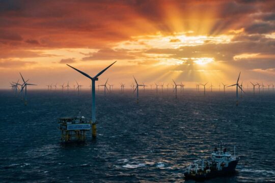 Unzählige Windturbinen eines Offshore-Windparks erstrecken sich im Sonnenaufgang über die raue Nordsee – ein sichtbarer Ausbau Windenergie Nordsee.