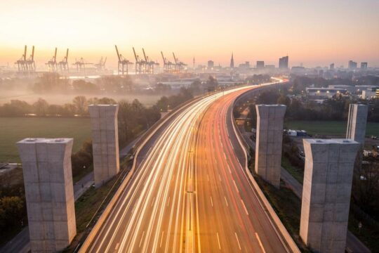 Achtspurige A7 Hochstraße Elbmarsch in Hamburg bei Dämmerung. Fließender Verkehr nach dem A7 Ausbau Hamburg mit Lichtspuren und Hafenkränen im Hintergrund.