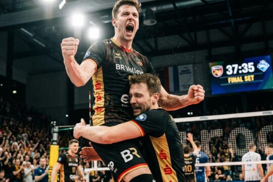 BR Volleys Spieler feiern euphorisch den BR Volleys Sieg Friedrichshafen. Einer springt jubelnd hoch, ein Teamkollege umarmt ihn erleichtert.