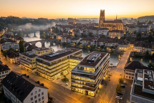 Abendliche Ansicht von Freiburg: Moderne Bürogebäude und die historische Altstadt am Fluss Saane spiegeln den attraktiven Wirtschaftsstandort Kanton Freiburg wider.