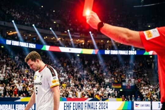Tom Kiesler erhält im EM Finale die Rote Karte: Ein Schiedsrichter hält sie hoch, während der deutsche Spieler resigniert den Kopf senkt. Eine dramatische Szene.