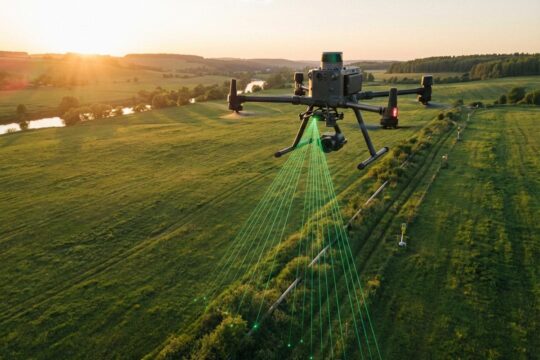 Ein Vermessungs-Multikopter schwebt über einer Pipeline in grüner Abendlandschaft. Laserstrahlen erfassen präzise Daten für die digitale Pipelinevermessung mit Drohnen.