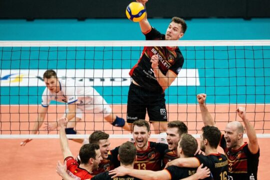 BR Volleys Spieler erzielt im Sprung den Matchball, der den BR Volleys Sieg Friedrichshafen besiegelt. Jubelndes Team umarmt sich euphorisch.
