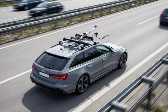 Schnell fahrendes Auto auf der Autobahn mit Skiern auf dem Dach. Ein gelockerter Gurt und ein verrutschter Ski warnen vor mangelhafter Ladungssicherung Skier.