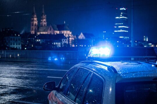 Dramatische Nachtszene in Basel: Pulsierendes Blaulicht eines Einsatzfahrzeugs spiegelt sich auf nassem Asphalt, stellvertretend für Blaulicht Meldungen Region Basel.