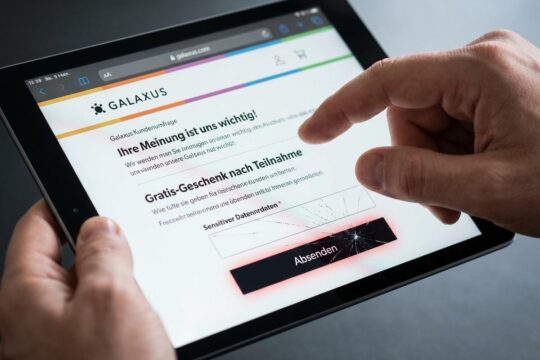 Eine Hand schwebt über dem Screen eines Smartphones, der eine verlockende, doch gefälschte Galaxus Umfrage mit bedrohlichem roten Schimmer zeigt.