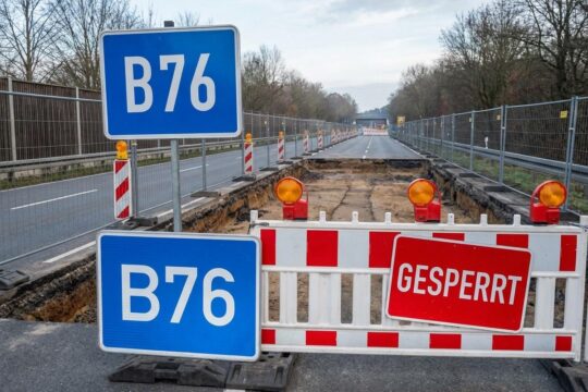 Blaues B76-Schild vor rot-weißen Absperrungen auf einer aufgerissenen Straße. Die B76 Sperrung Plön ist wegen Sanierungsarbeiten eingerichtet.