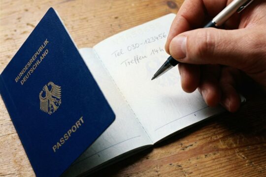 Ein Kugelschreiber schwebt über einer leeren Seite eines geöffneten deutschen Reisepasses, daneben sind Notizen sichtbar. Der Reisepass als Notizbuch ist ungültig.