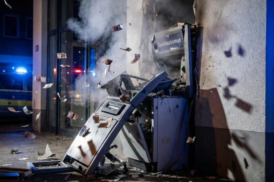 Dramatische Szene: Ein Geldautomat ist nach einer Geldautomatensprengung nachts massiv beschädigt, Trümmer und Rauch zeugen von der Gewalt der Detonation.