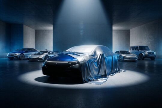 Ein visionäres, neues Mercedes-Benz Modell im Rampenlicht, Front teilweise verhüllt. Im Hintergrund moderne Fahrzeuge der Mercedes Produktoffensive.