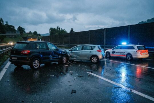 Der Nachklang eines Verkehrsunfalls St. Gallen im Stephanshorntunnel: Beschädigte PKWs und Blaulicht der Kantonspolizei auf nassem Asphalt.