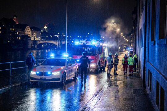 Nächtliche Szene mit Blaulichtfahrzeugen, nassem Asphalt und Einsatzkräften in Basel als Blaulichtmeldungen Region Basel.