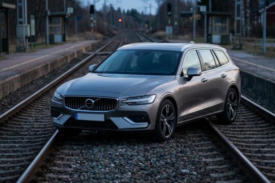 Ein modernes, unbeschädigtes Auto auf Gleisen steht verlassen im Gleisbett bei Ockenheim in blauer Dämmerung, leicht unscharf im Hintergrund Bahnsteige.
