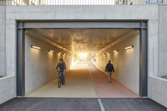 Einladender, heller Eingang der modernen Fuss- und Velounterführung Beginenweg St.Gallen. Ein Radfahrer und ein Fussgänger nutzen die klar getrennten Wege.