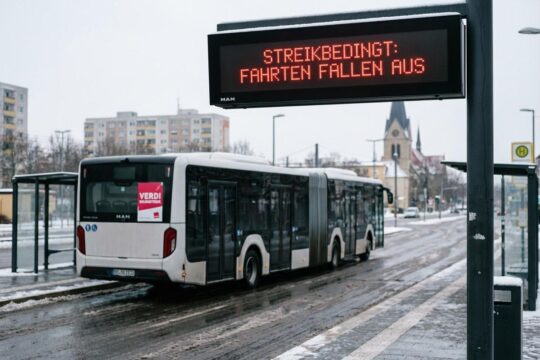 Warnstreik Nahverkehr Sachsen-Anhalt: Eine digitale Anzeigetafel an einer leeren Haltestelle zeigt 'STREIKBEDINGT: FAHRTEN FALLEN AUS'.