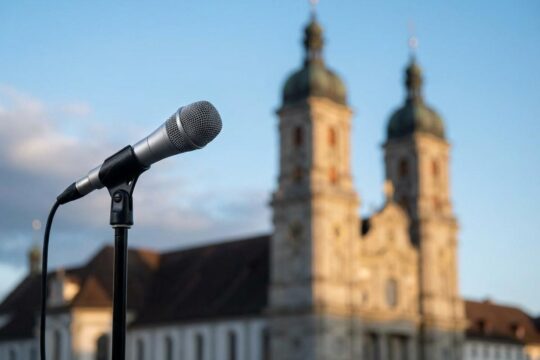 Ein professionelles Broadcast-Mikrofon vor den majestätischen Türmen der Stiftskirche St. Gallen, das die neuesten News St Gallen symbolisiert.